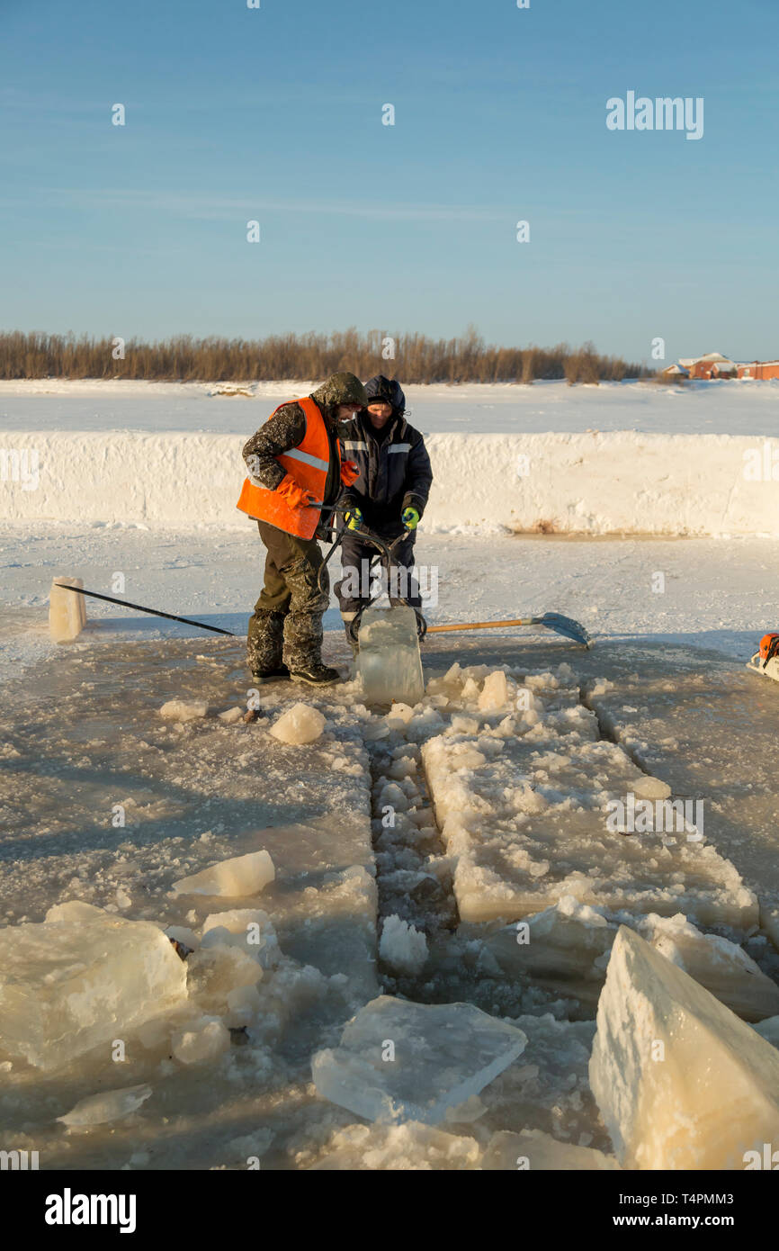 Tirez le bloc de glace travailleurs hors du trou avec des pinces en acier Banque D'Images