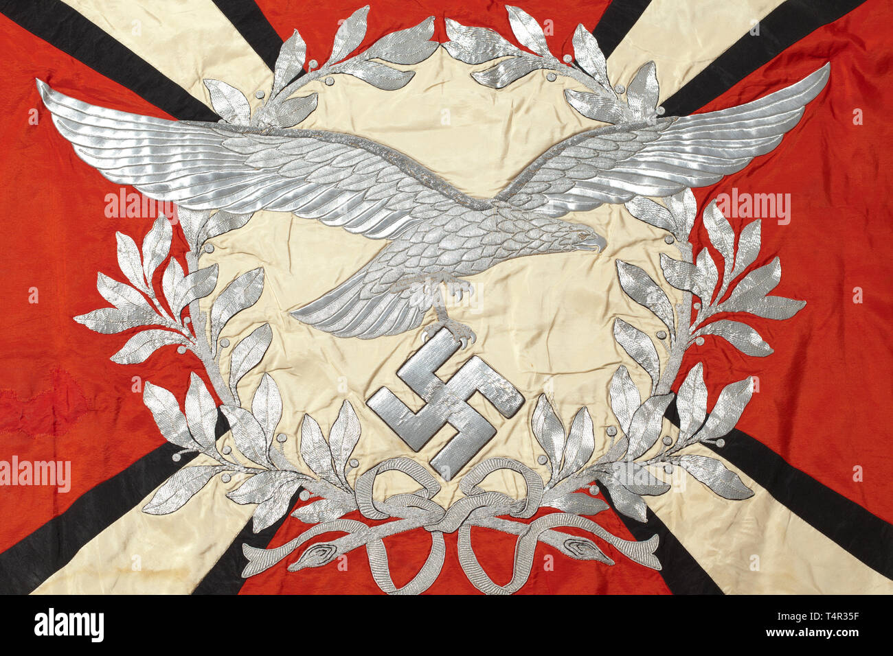 Une unité d'artillerie flak Drapeau effectué entièrement de soie rouge avec bordure argent sur trois côtés. Avec un disque blanc sur les deux côtés entouré par une couronne de laurier brodée d'argent. Un côté affiche un brodé silver eagle de la Luftwaffe dans le centre de l'ampleur au-delà de la Couronne, et l'autre disque porte une croix de fer. Diagonale quatre rayons blancs avec bordure noire, s'élargissant vers les coins, chacun portant une arme à d'argent, croix gammée de soie noire à l'angle. Des couleurs fraîches, des traces d'ongles sur le fourreau, un patch avec un tissu en soie d'origine, à peine perceptibles les taches. C Dimensions, Editorial-Use-seulement Banque D'Images