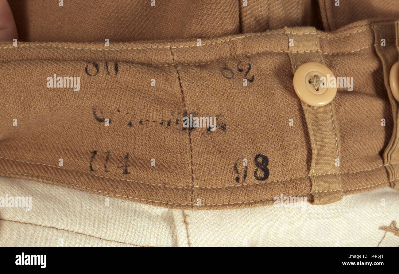Une paire de pantalon avec poche de jambe (soi-disant "Ramcke-Hose') pour les régions tropicales de l'habillement de la Luftwaffe depot morceau avec Reich numéro d'usine la variante de la question dans de solides brown cotton twill avec boutons en résine synthétique marron. Ceinture intégrée avec fermoir coulissant, a soulevé l'arrière et boutons pour porter avec bretelles, couverts de mouche, oblique bouton poches avant, la jambe droite et poche intégrée poche arrière avec fermeture des volets. Jambe droite fermeture avec bornes de bandes. La base de la chemise en tissu, Sacs de poche de toile blanche, RB nombre et de la taille des emboutis. Color-frais, avec le papier inutilisé t, Editorial-Use-seulement Banque D'Images