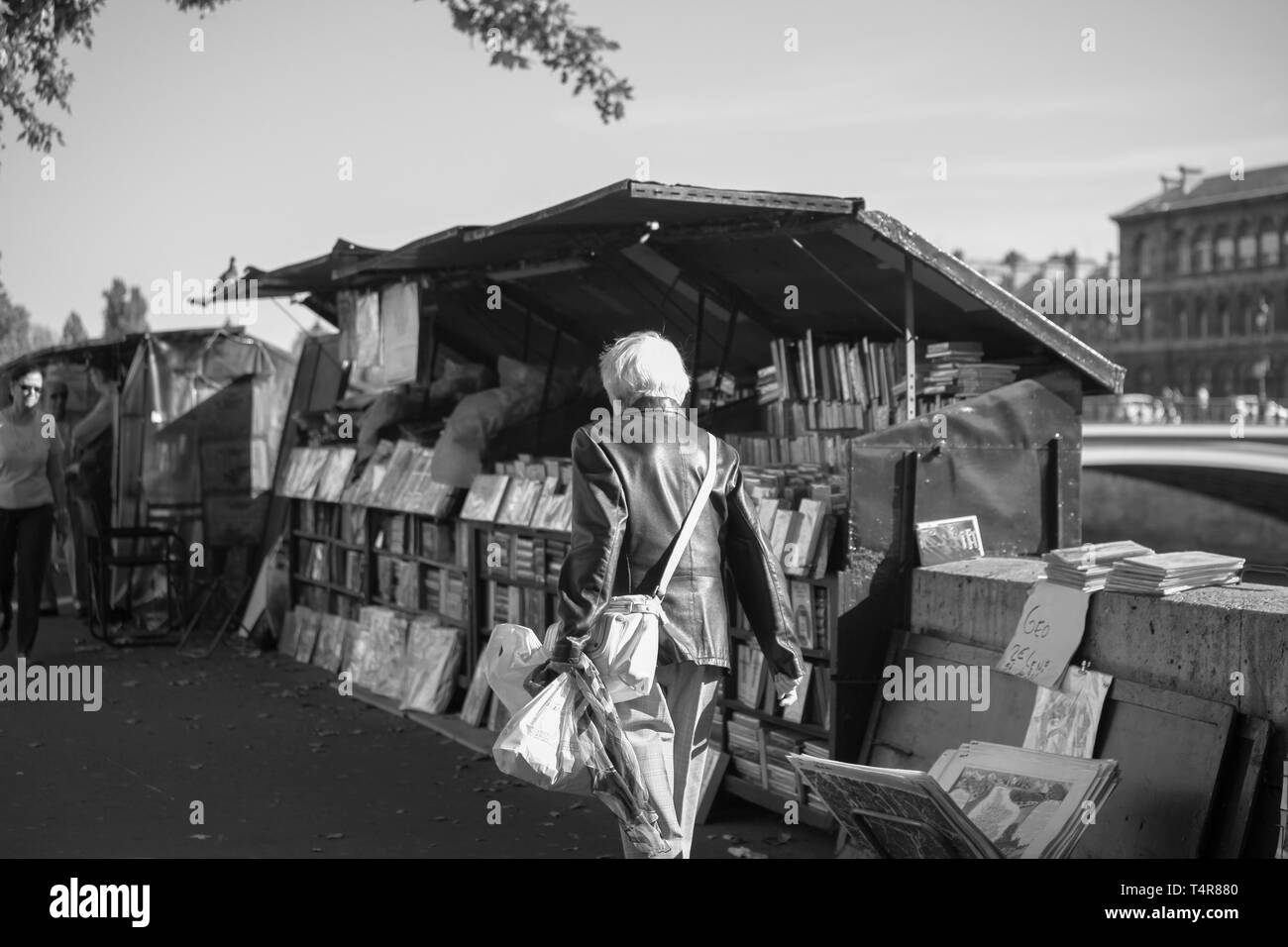 Femme à la navigation sur le trottoir du marché du livre, Quai de Seine, Paris, France Banque D'Images