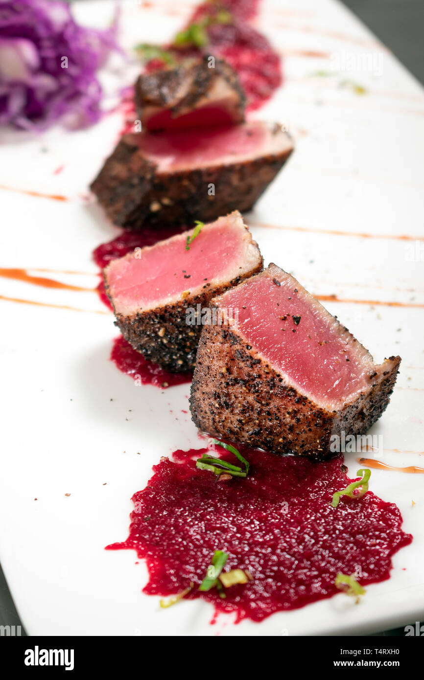Thon poêlé gastronomique en croûte de poivre noir de betterave et coulis de framboise Banque D'Images