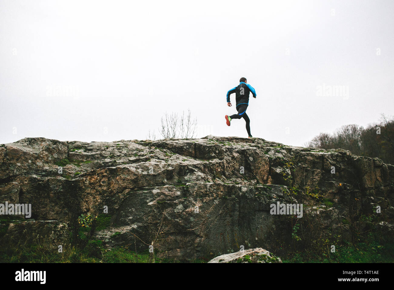 Sport running man in cross country trail run. Runner mâle l'entraînement à l'exercice et le saut à l'extérieur dans une vue magnifique sur la montagne nature paysage Banque D'Images