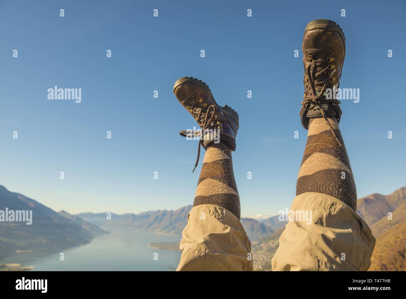 Des chaussures de randonnée et les jambes en l'air, de montagnes et lac Lago Maggiore, Tessin, Suisse Banque D'Images