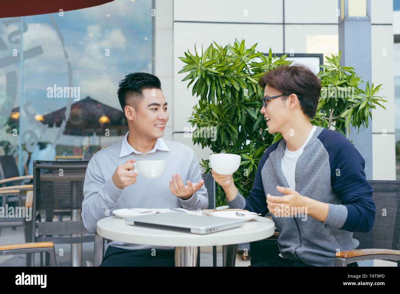 Deux jeunes hommes sont en pleine discussion dans un café. - Image Banque D'Images