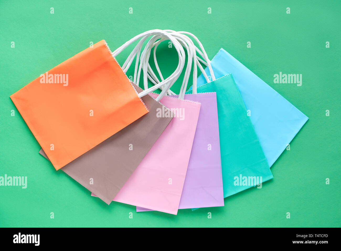 Sacs de papier assortis de diverses couleurs pastel, télévision jeter sur papier fond vert Banque D'Images