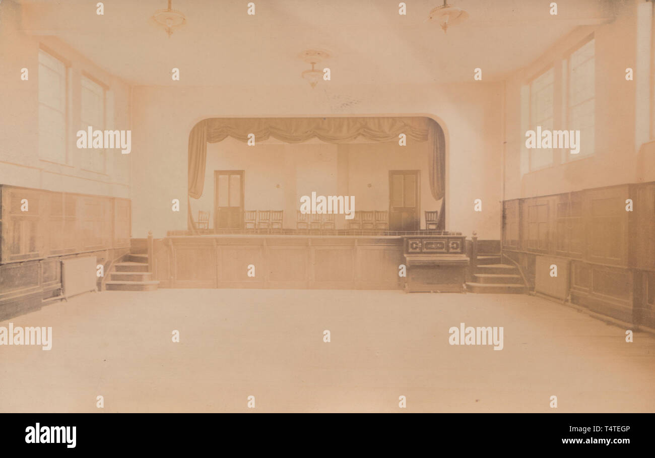Vintage Carte postale photographique montrant l'intérieur d'un bâtiment britannique historique. Semble être un Village Hall avec une scène de théâtre Banque D'Images