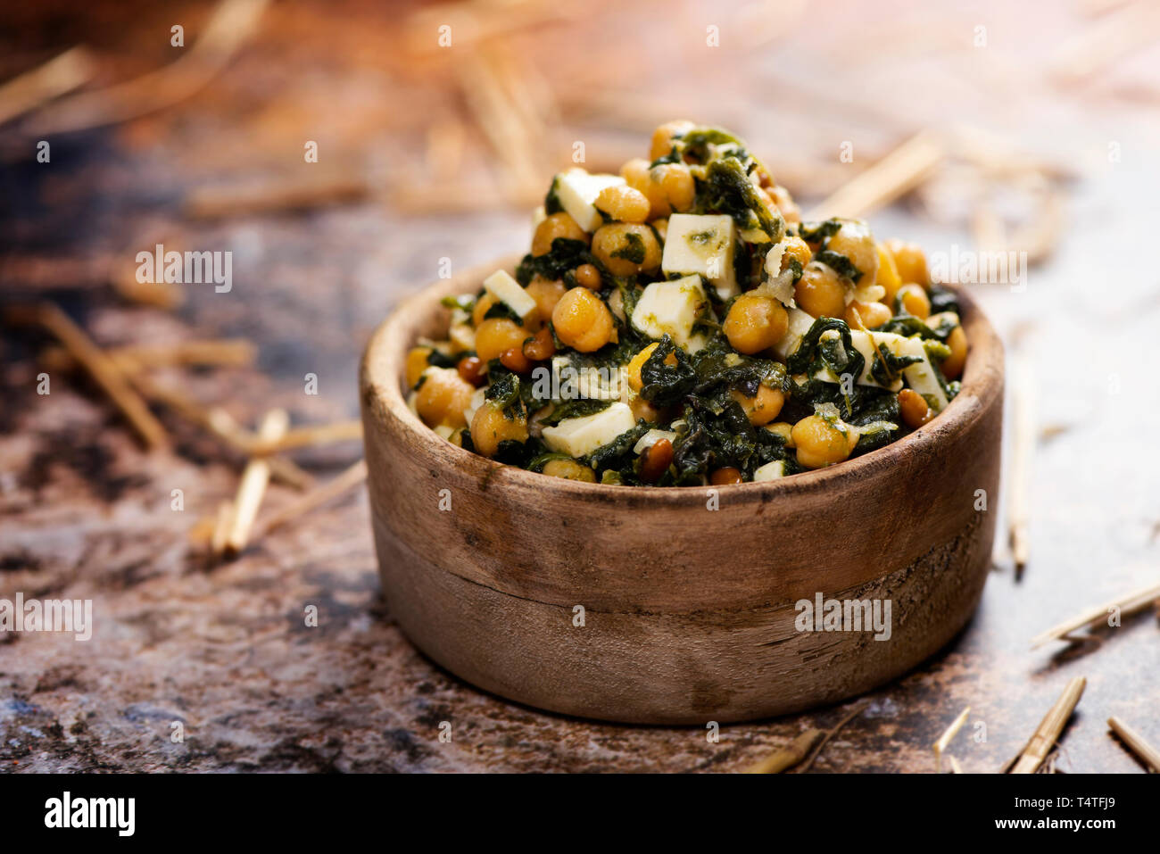 Une salade de pois chiches, avec les épinards, les pignons, l'oignon et fromage, servi dans un bol en buis rustique, placée sur une table rustique Banque D'Images