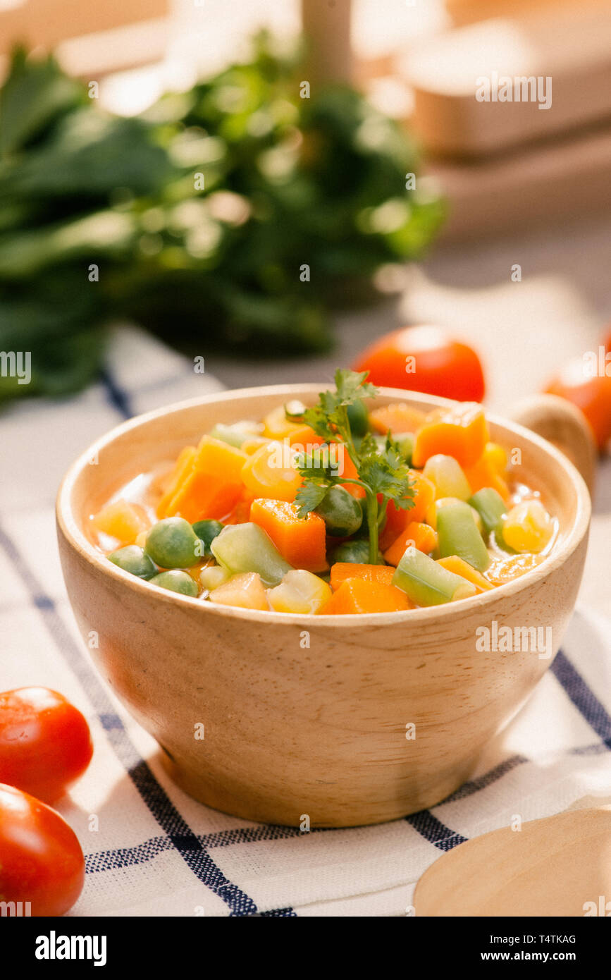 Louche de jeunes légumes fraîchement récoltés à la vapeur y compris les carottes, en Coupe ondulée, de pois et de pommes de terre pour un accompagnement sain pour le dîner Banque D'Images