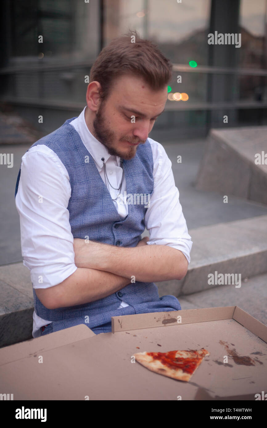 Un jeune homme, 29 ans, résistant de manger sa nourriture, à la recherche d'une pizza. Banque D'Images