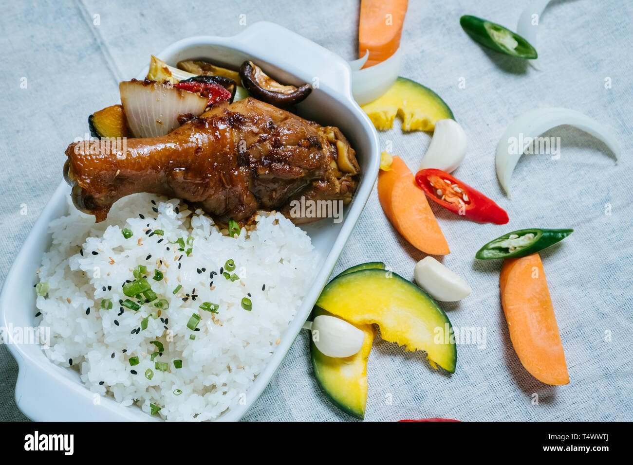 Cuisse de poulet frit, du riz, des tranches de tomate et oignon, piment rouge sur la plaque en plastique blanc et fond clair Banque D'Images