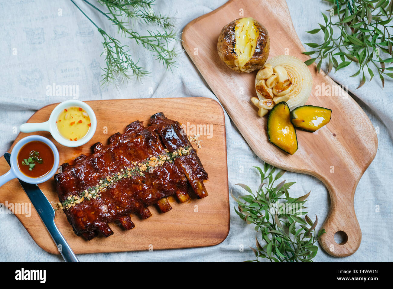 Côtes levées au barbecue avec du miel se trouve sur une vieille planche en bois vintage rustique, sauce, sauce de poisson, l'aneth, les oignons sur la table en haut, bas, angle shot Banque D'Images