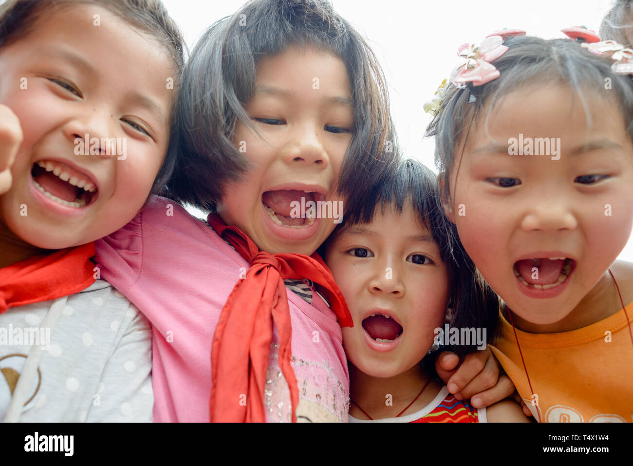 Quatre jeunes filles de l'école dans le groupe hug, rire et crier. Guangxi, région du sud de la Chine centrale. Banque D'Images