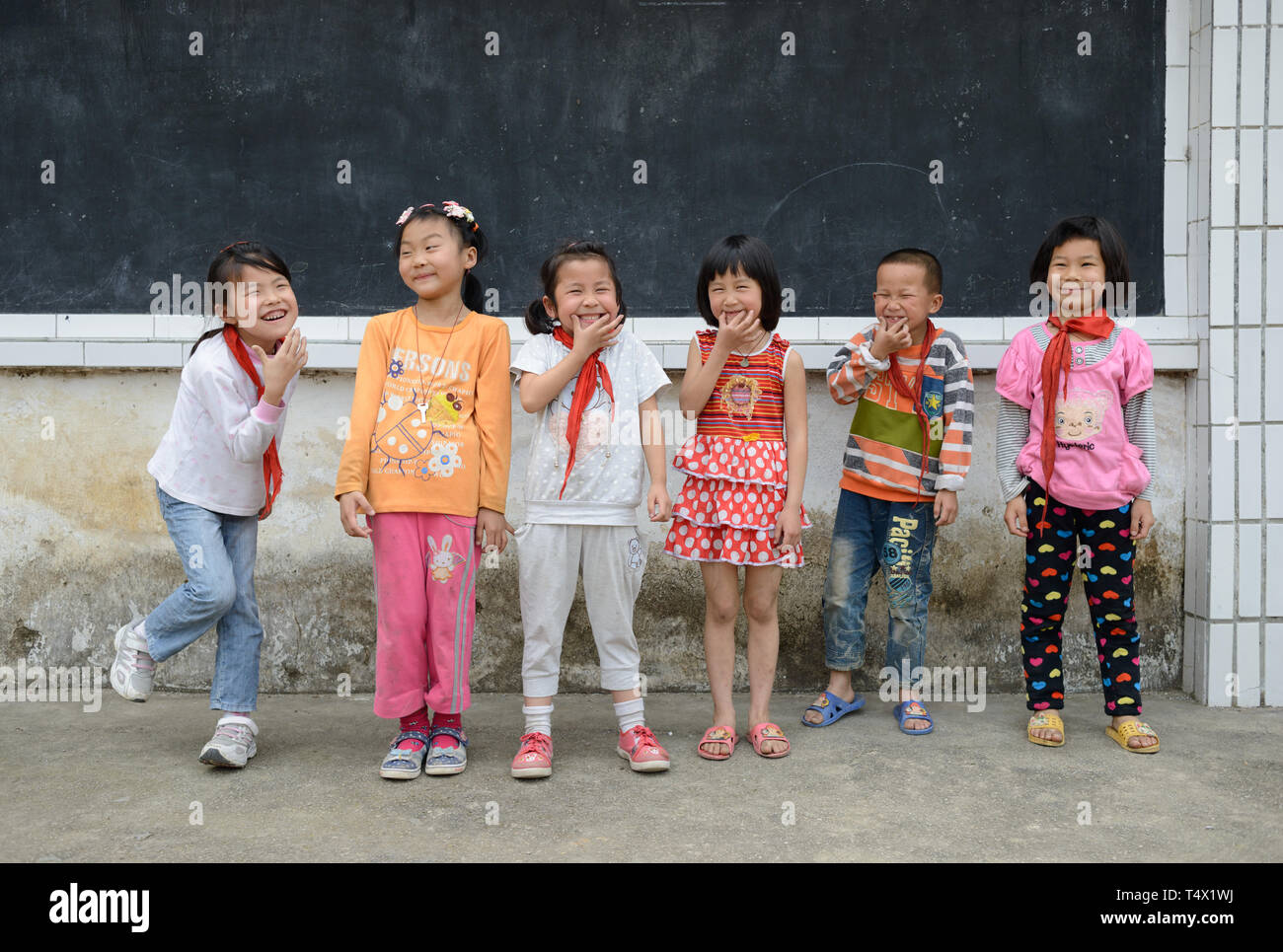 L'âge des enfants de l'école primaire s'alignent pour une photo, rire et jouer, dans la cour de l'école en milieu rural de la région de Guangxi, dans le sud de la Chine centrale. Banque D'Images