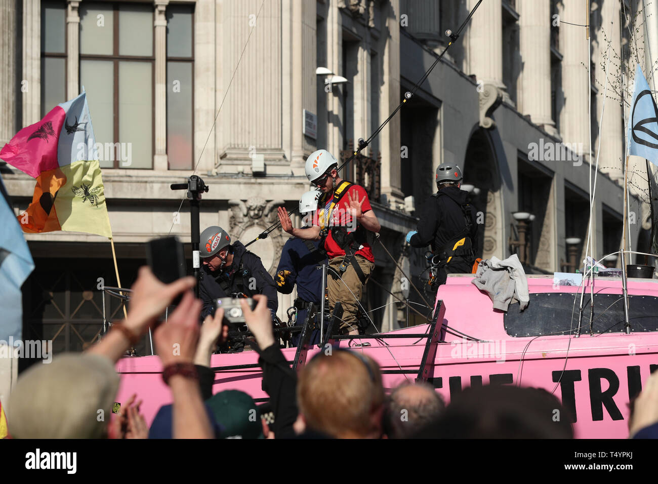 L'un des derniers manifestants rébellion Extinction attaché à la 'vérité' bateau, qui lui-même collé au mât, est détaché par la police à Oxford Circus, Londres. Banque D'Images