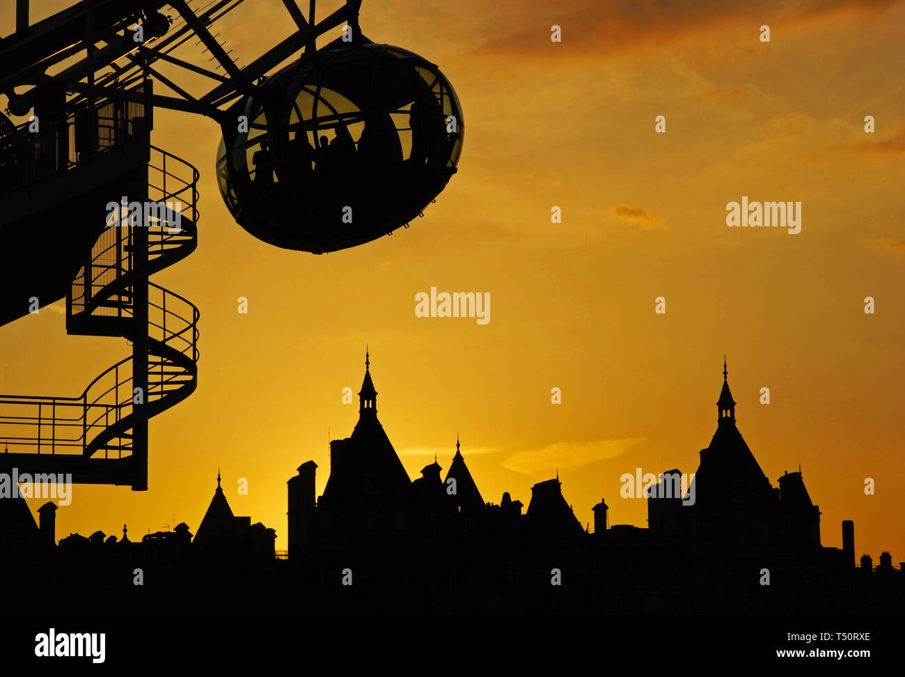 Silhouette d'une London Eye et des bâtiments contre un coucher de ciel orange. London, UK Banque D'Images