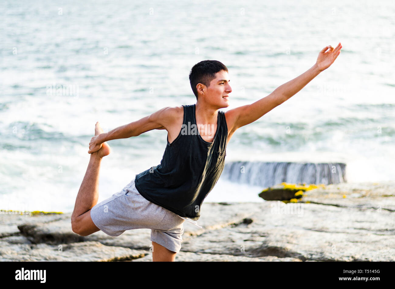Homme en bonne santé pratiquant le yoga. Stretching en position naturelle dans Natarajasana, beau paysage de mer, coucher de soleil, nature, concept pour faire de l'exercice, les soins de santé Banque D'Images