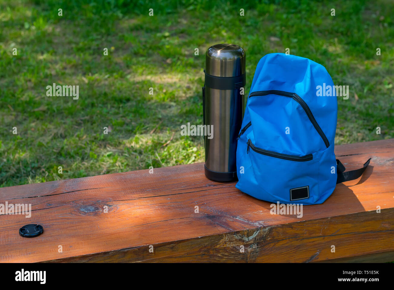 Sac à dos et le thermos pour le camping sur un banc de bois nature Banque D'Images