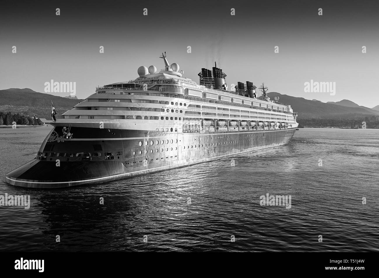 Moody photo en noir et blanc du géant Disney Cruise Ship, Disney Wonder, arrivant dans le port de Vancouver au lever du soleil. Colombie-Britannique, Canada. Banque D'Images