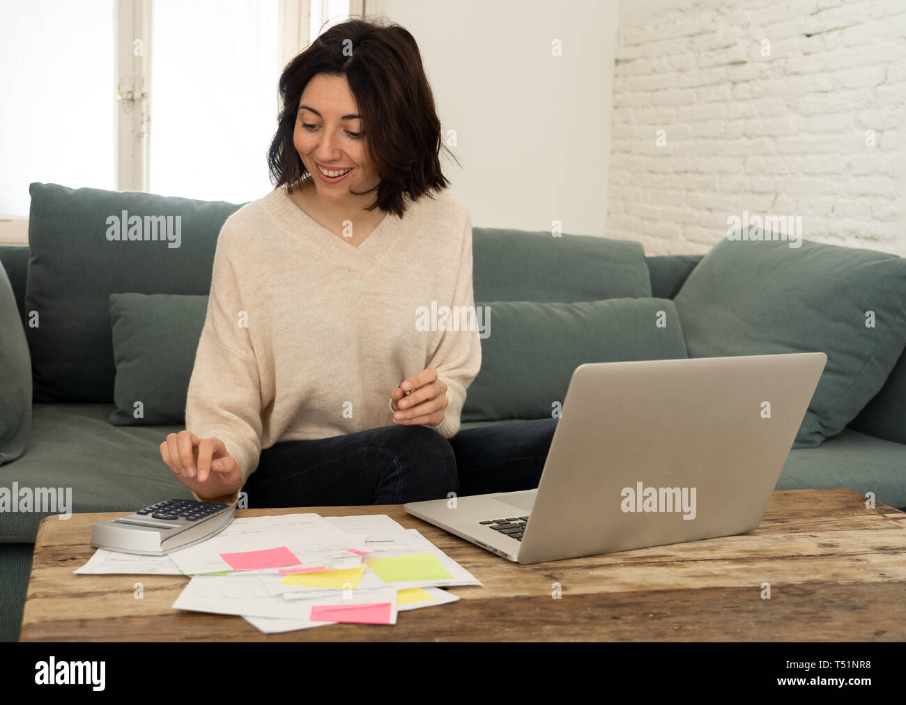 Femme au foyer ou femme entrepreneur heureux de payer des factures, calcul de coûts, frais d'hypothèque, les taxes, avec documents, ordinateur portable et calculatrice à la maison. Dans la maison Banque D'Images