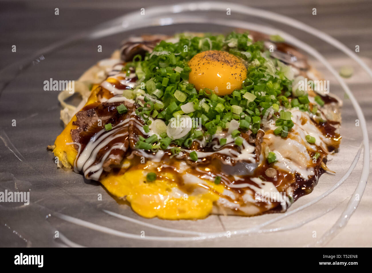 Okonomiyaki, une pizza japonaise / pancake contenant une variété d'ingrédients, sur le plateau Banque D'Images