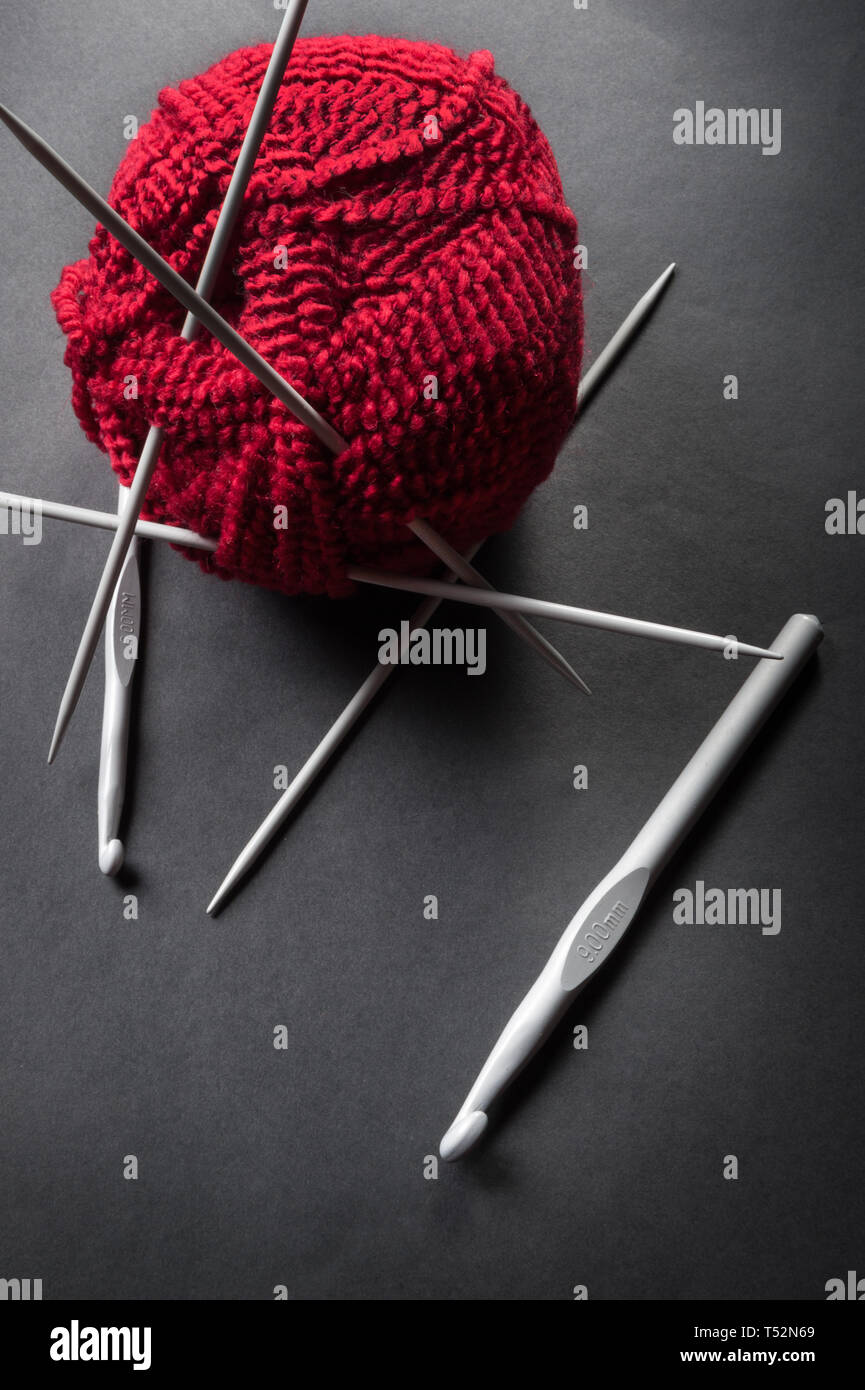 Balle de laine et des aiguilles à tricoter sur fond sombre Banque D'Images