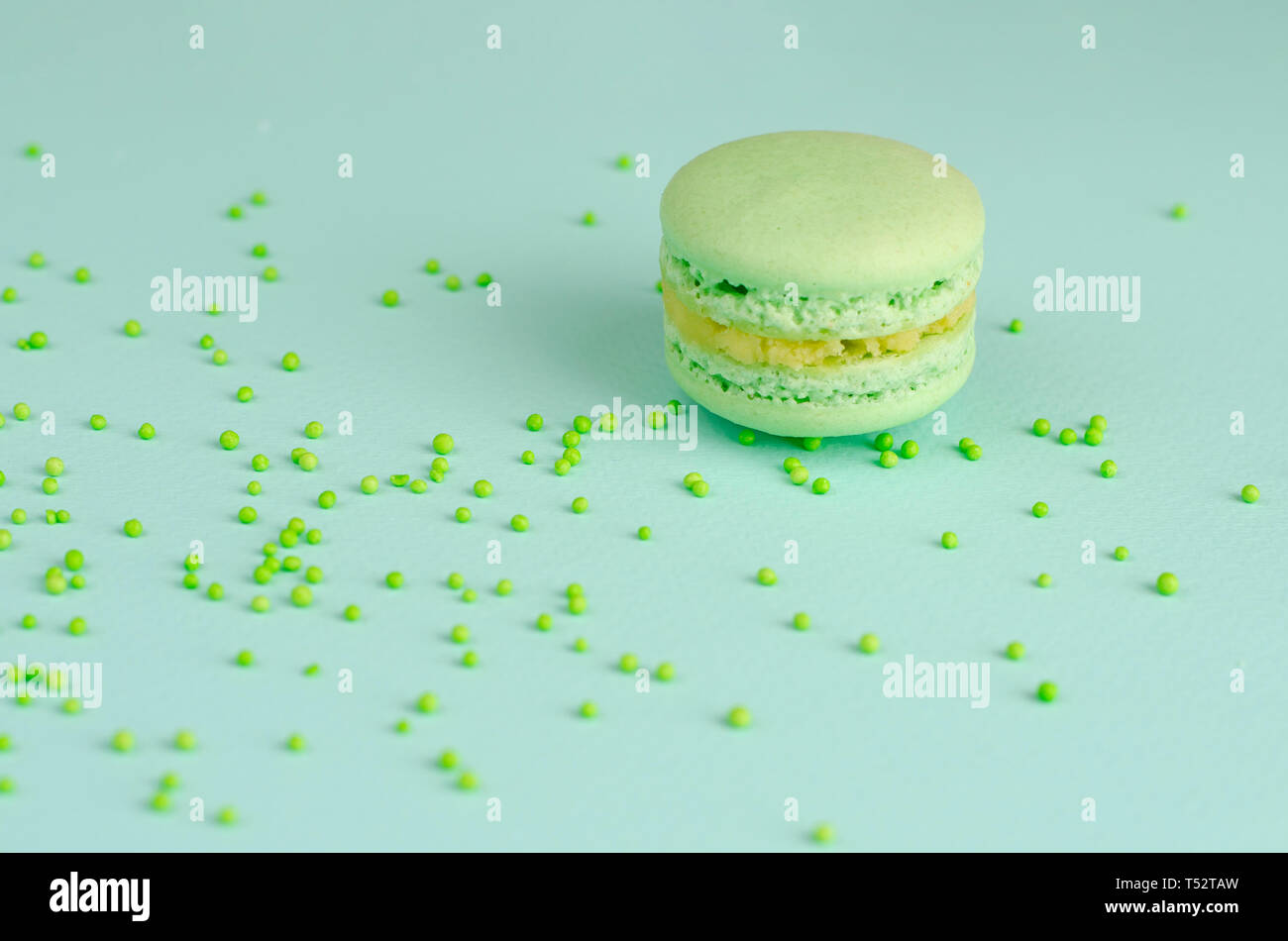Macaron macaron vert unique ou sur fond de menthe pastel avec paillettes. L'espace pour le texte. Carte d'invitation ou de voeux. Journée sans diète Banque D'Images