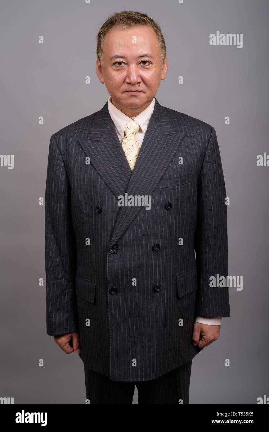 Portrait of mature Asian businessman contre l'arrière-plan gris Banque D'Images