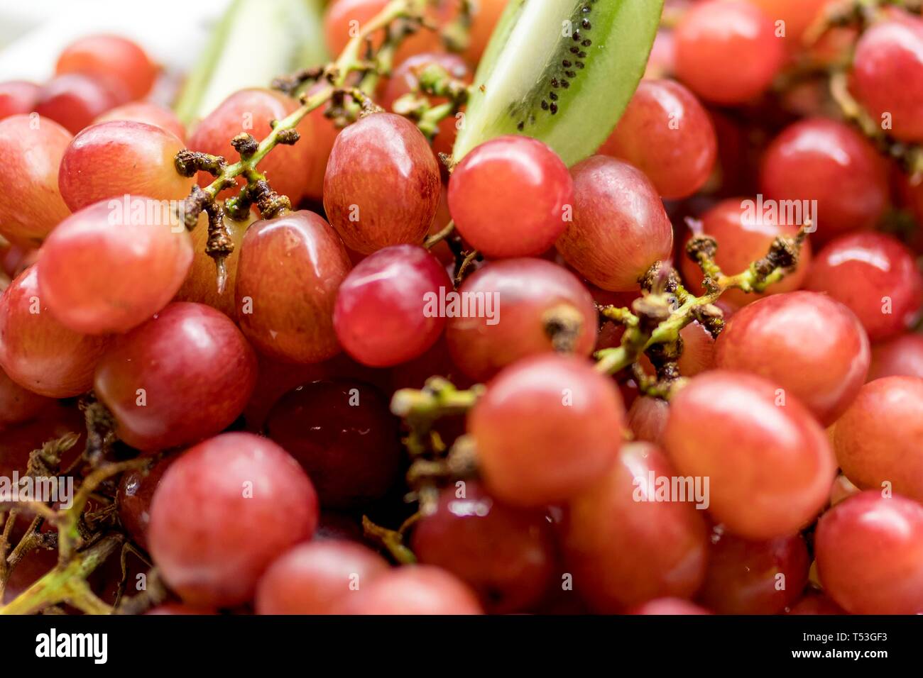 Close up de raisins rouges mûrs et sur un buffet de luxe habillés avec les kiwis pour un petit-déjeuner sain ou le dîner. Banque D'Images