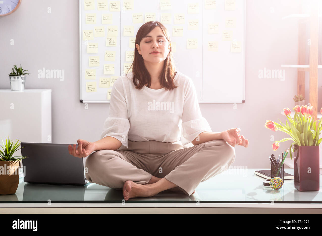 Young Businesswoman Sitting on Desk In Office Banque D'Images