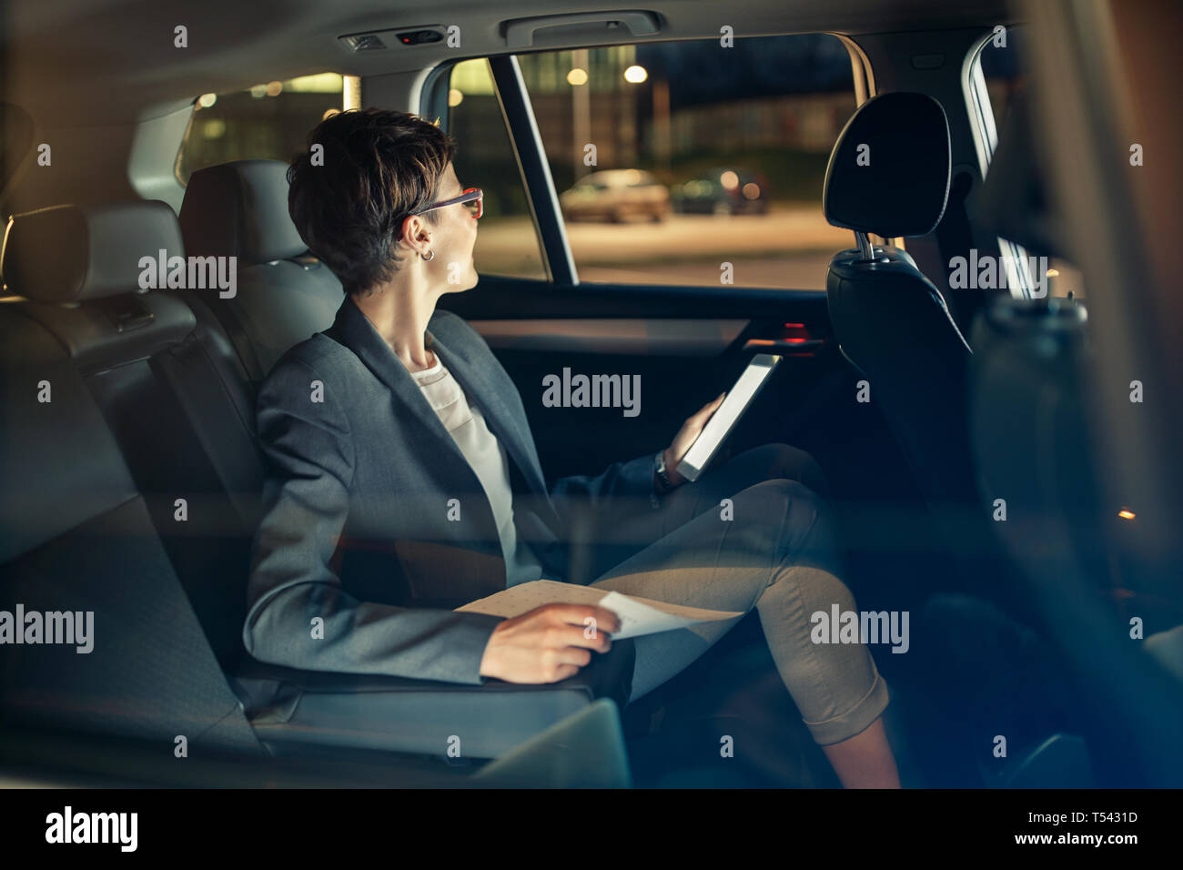 Femme d'affaires qui voyage avec voiture à siège arrière par nuit en voyage d'affaires Banque D'Images