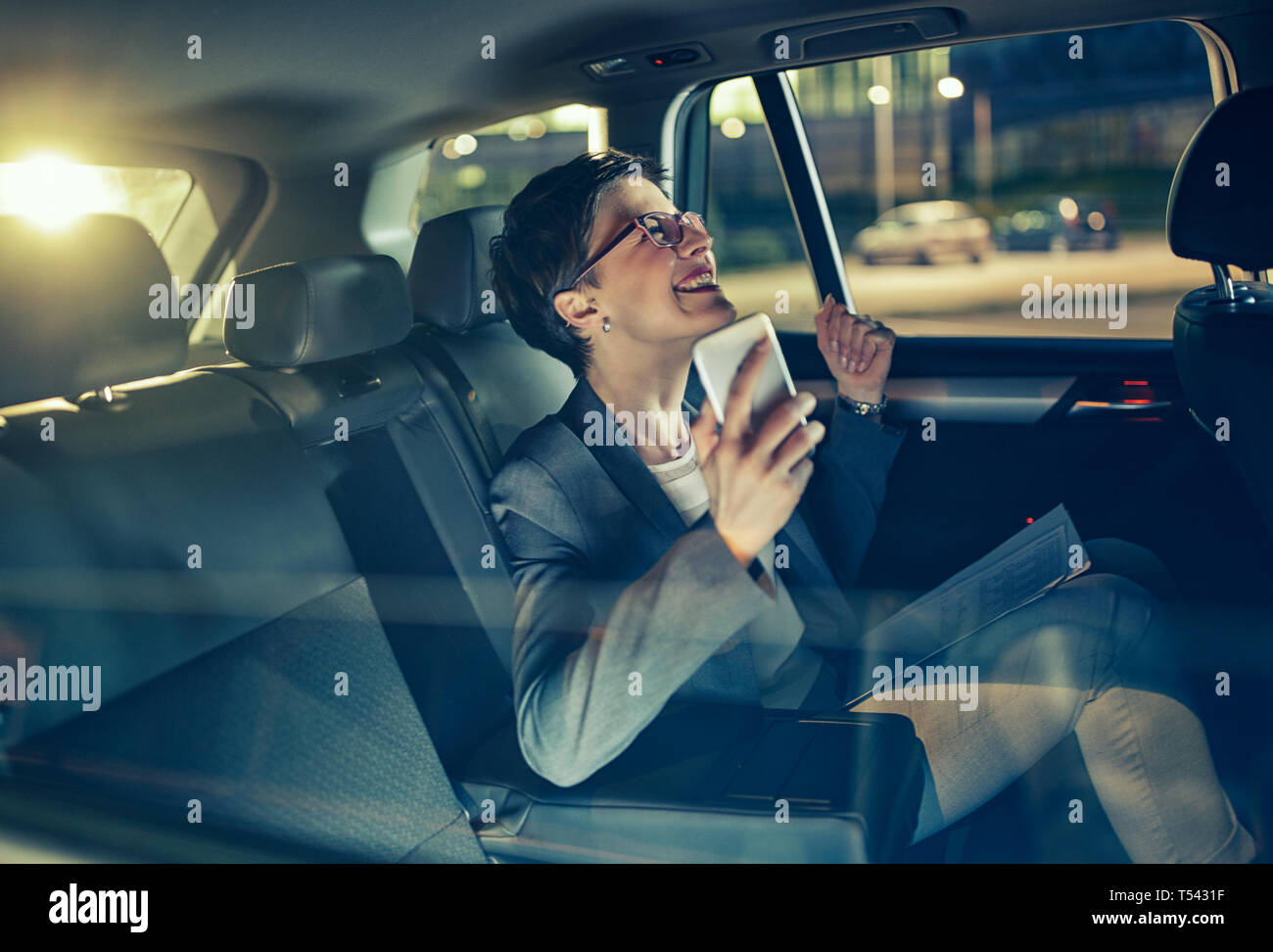 Happy business femme voyageant avec voiture à siège arrière par nuit en voyage d'affaires Banque D'Images