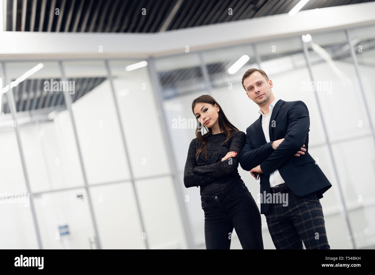 Un homme d'affaires et femme debout dos à dos avec des sourires sur leurs visages Banque D'Images