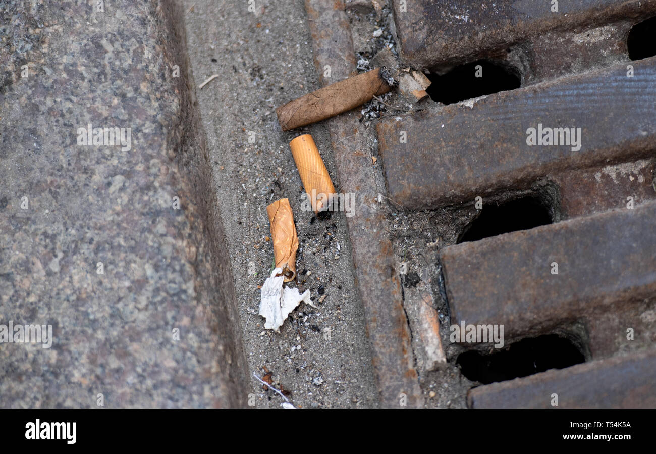 Hambourg, Allemagne. 18 avr, 2019. Les mégots sont situées sur la rue sur un couvercle de trou d'homme. Déchets de Hambourg watchers ont imposé autour de 6000 mises en garde et des amendes pour l'élimination illégale de déchets dans l'année. Selon un porte-parole, environ la moitié d'entre eux ont été dirigés contre les fumeurs qui simplement feuilleter leurs cigarettes sur la rue ou dans la nature. (Dpa 'presque 6000 amendes pour les pourboires et de chewing-gum sur les trottoirs de Hambourg") Crédit : Daniel Reinhardt/dpa/Alamy Live News Banque D'Images
