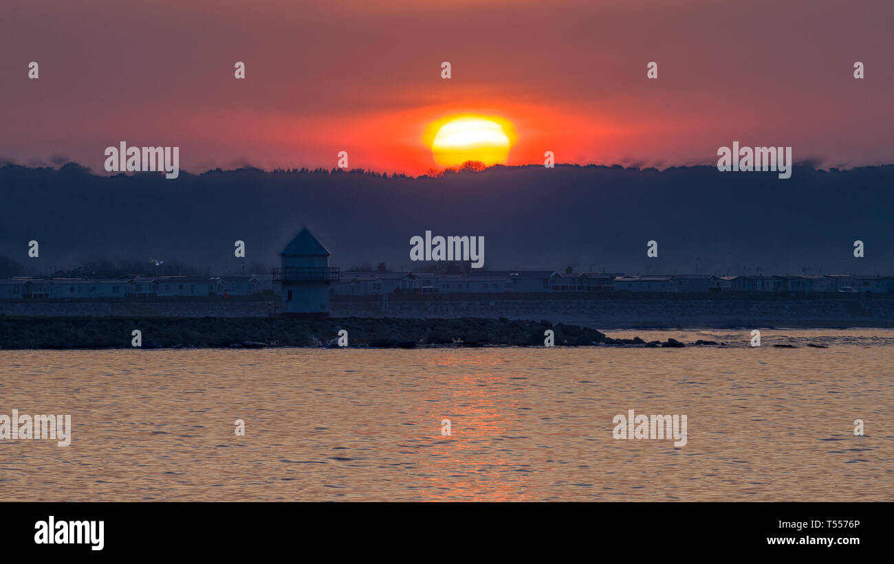 La tour des sauveteurs et le parc de caravanes de Trecco Bay photographiés à l'aube alors que le soleil se lève sur Ogmore-by-Sea photographié depuis la jetée de Porthcawl. Banque D'Images