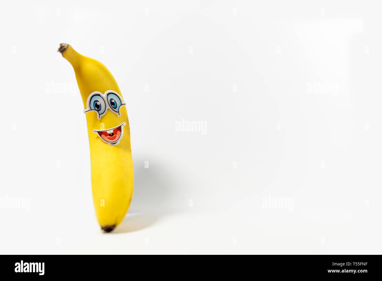 La banane jaune vif avec une bonne caricature comme visage pour encourager les enfants à manger sain, situé sur un fond blanc Banque D'Images