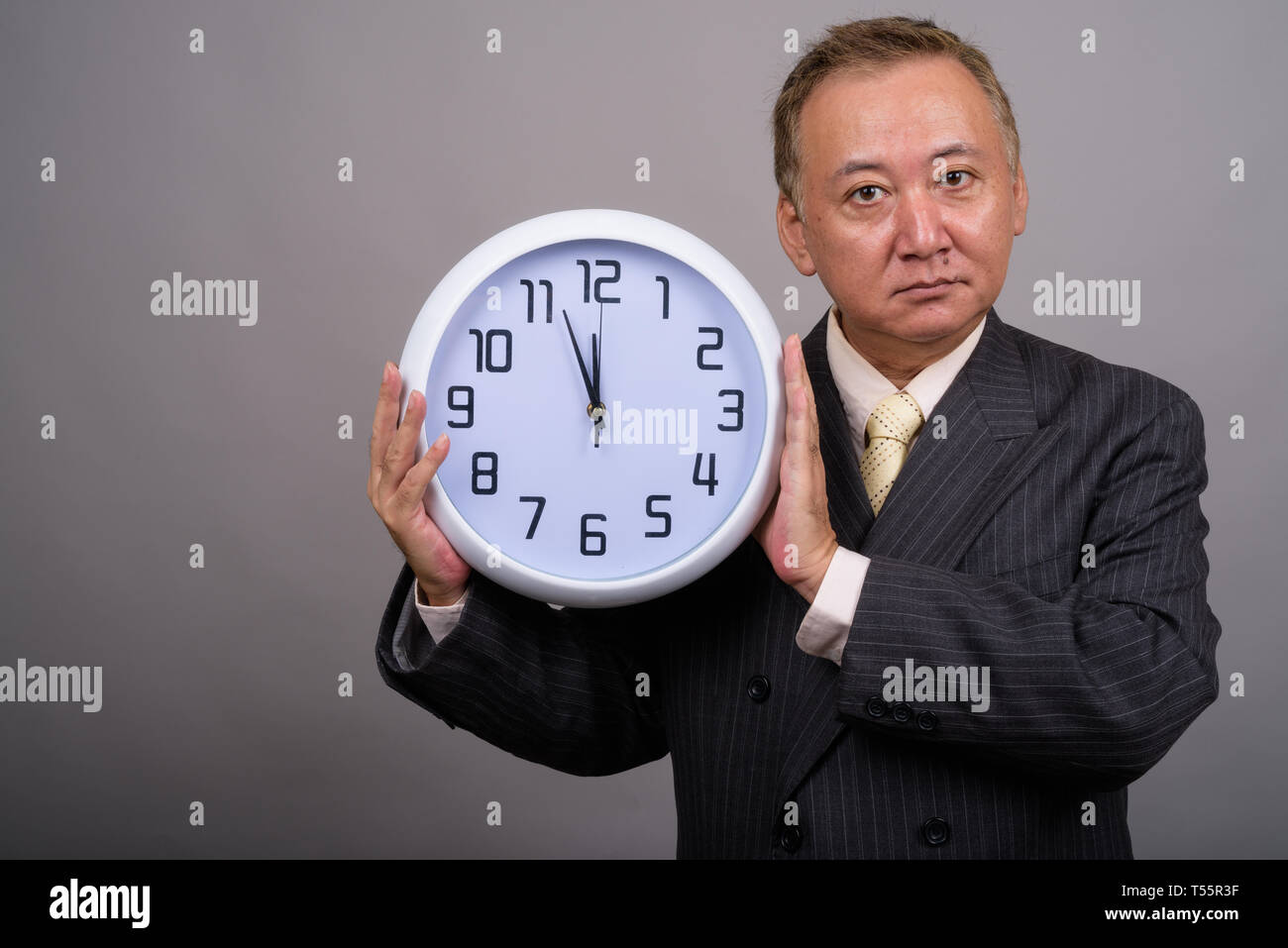 Portrait of mature Asian businessman contre l'arrière-plan gris Banque D'Images
