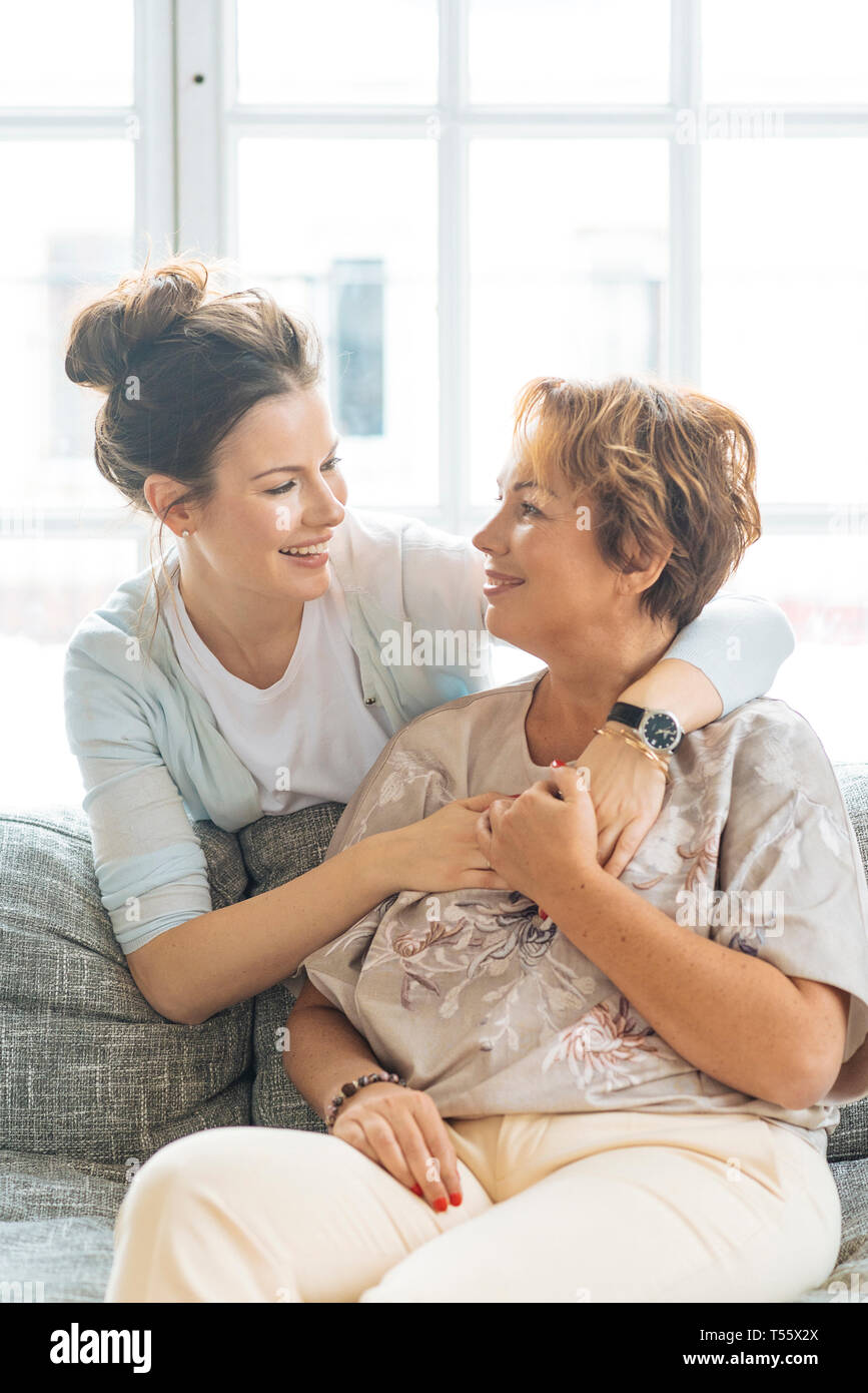 Mère et fille adultes hugging on sofa Banque D'Images