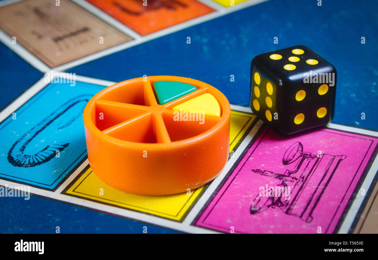 Londres, Royaume-Uni - 07 Avril 2019 : classique jeu de Trivial Pursuit avec die noir et pièces en plastique de couleur de différentes couleurs Banque D'Images