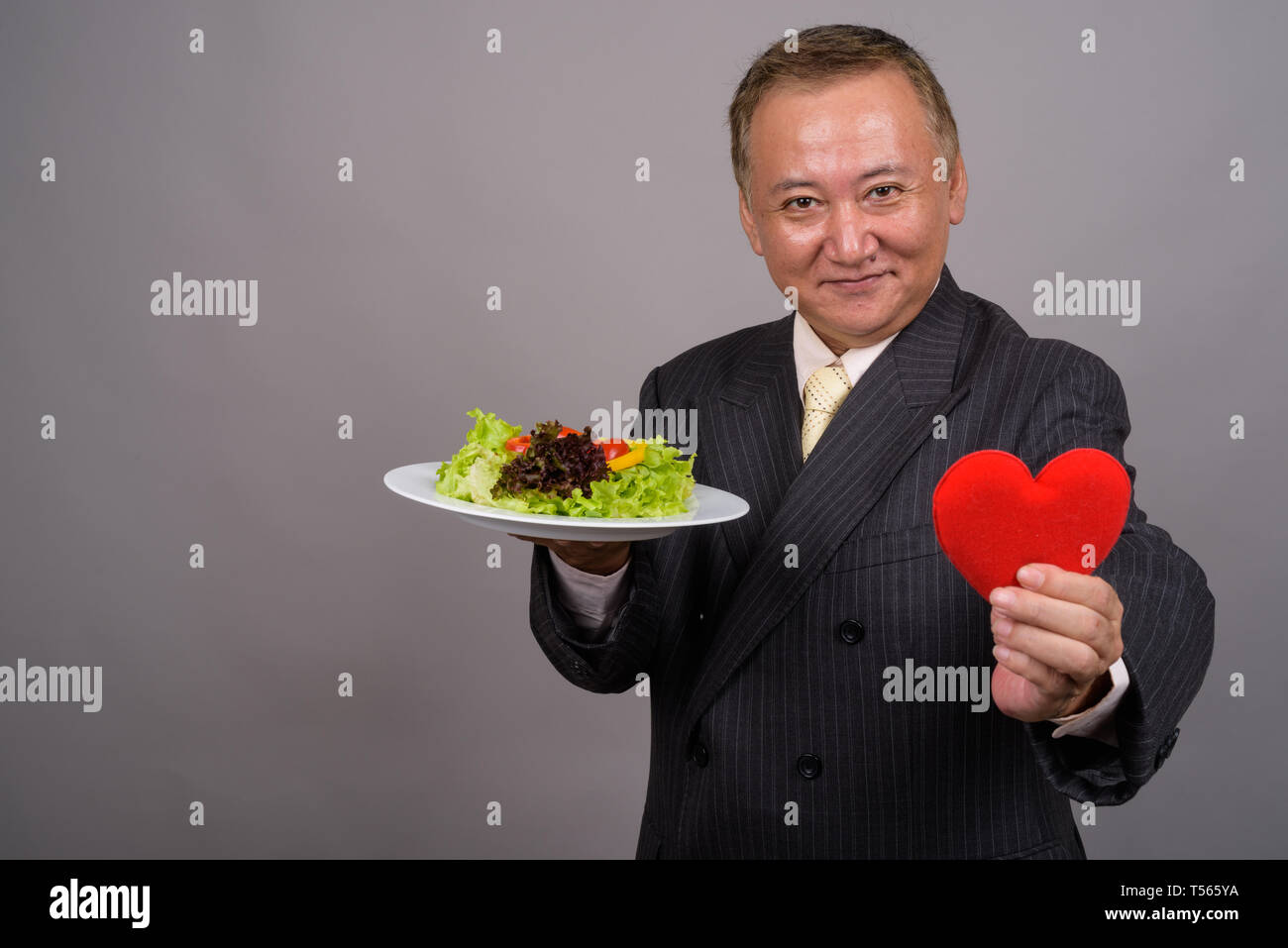 Portrait of mature Asian businessman contre l'arrière-plan gris Banque D'Images