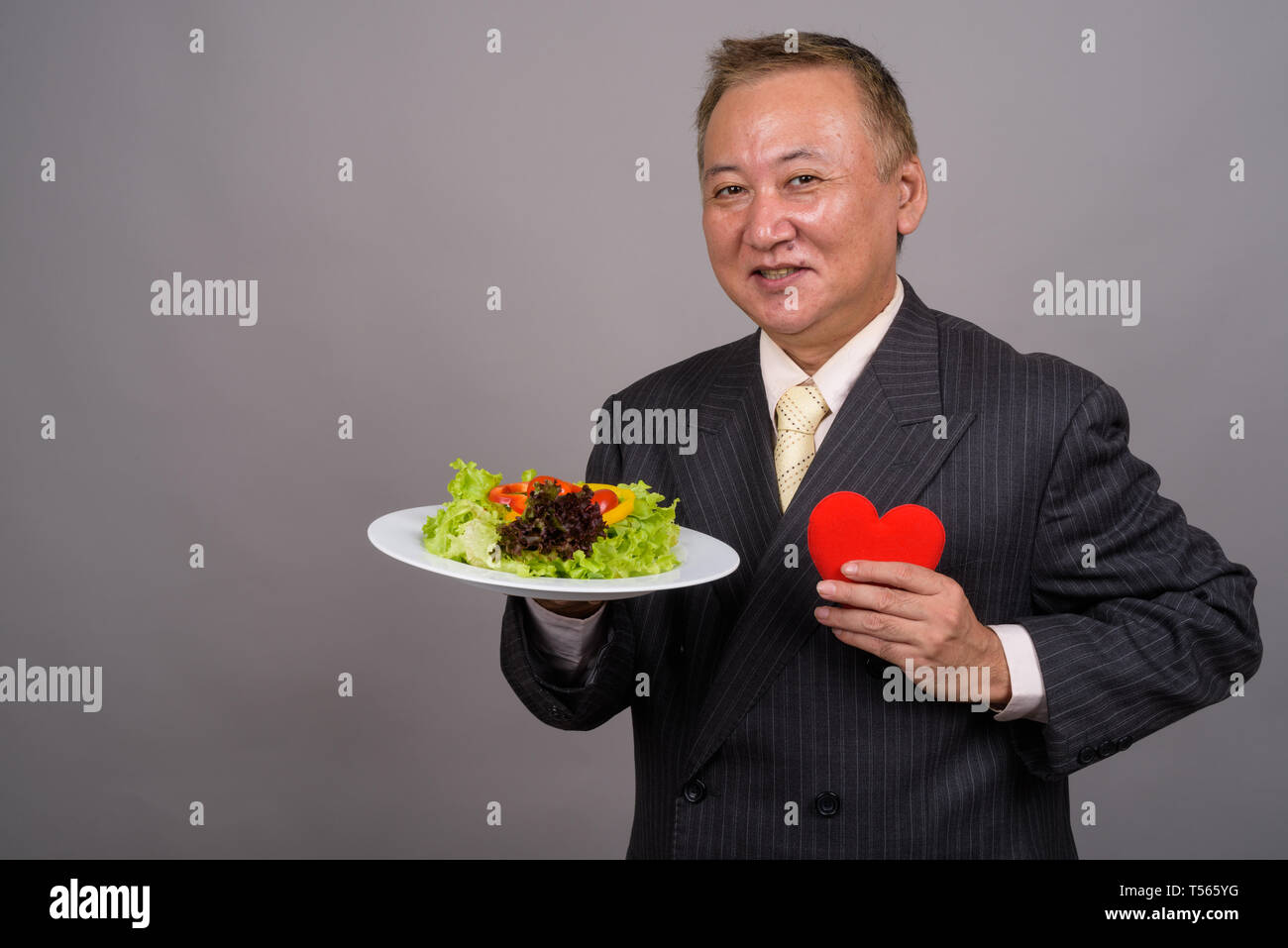 Portrait of mature Asian businessman contre l'arrière-plan gris Banque D'Images