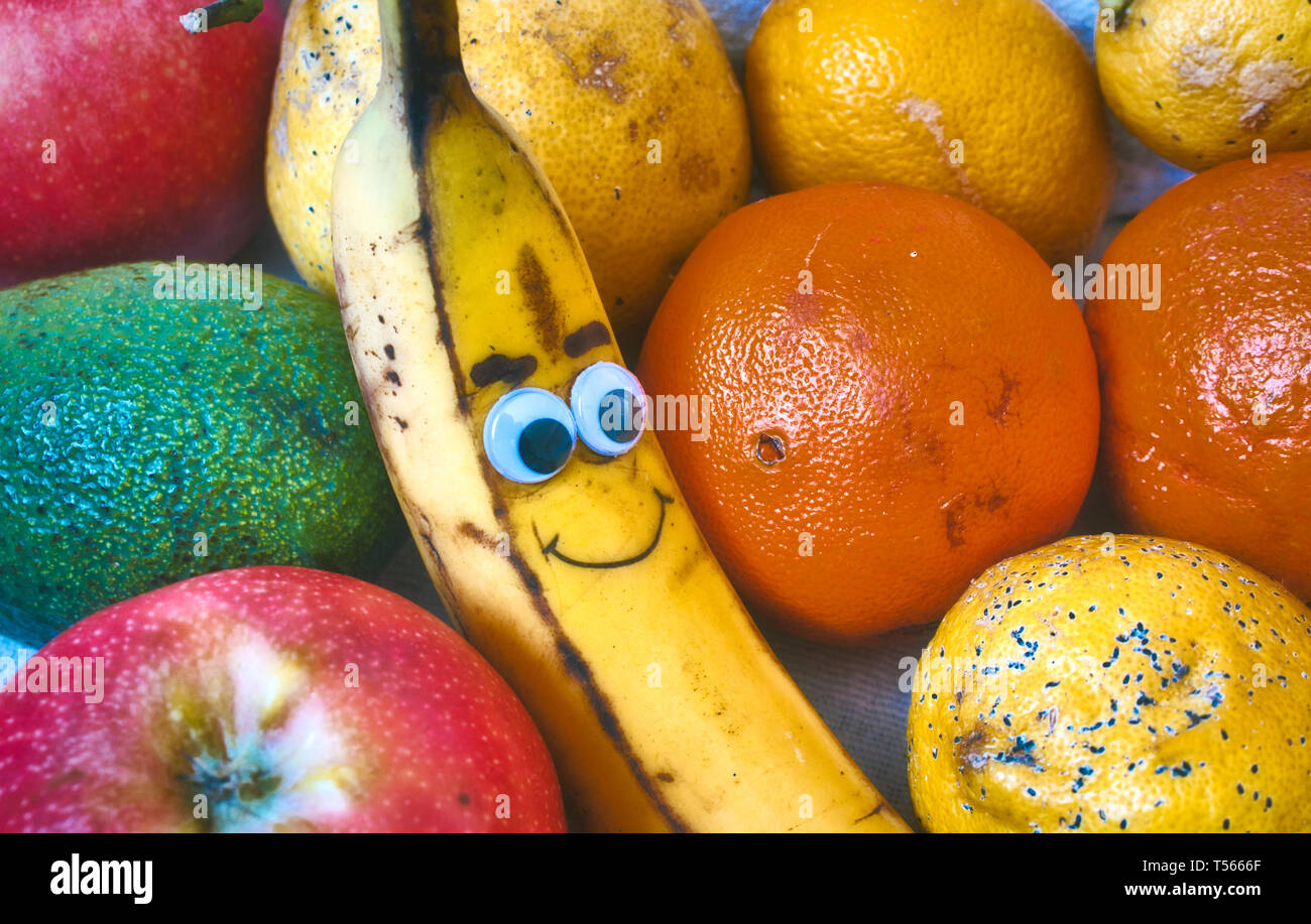 Un bol de fruits frais avec un smiley banane avec un visage dessiné sur Banque D'Images