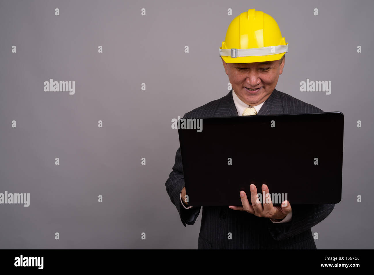 Mature Asian businessman construction contre l'arrière-plan gris Banque D'Images