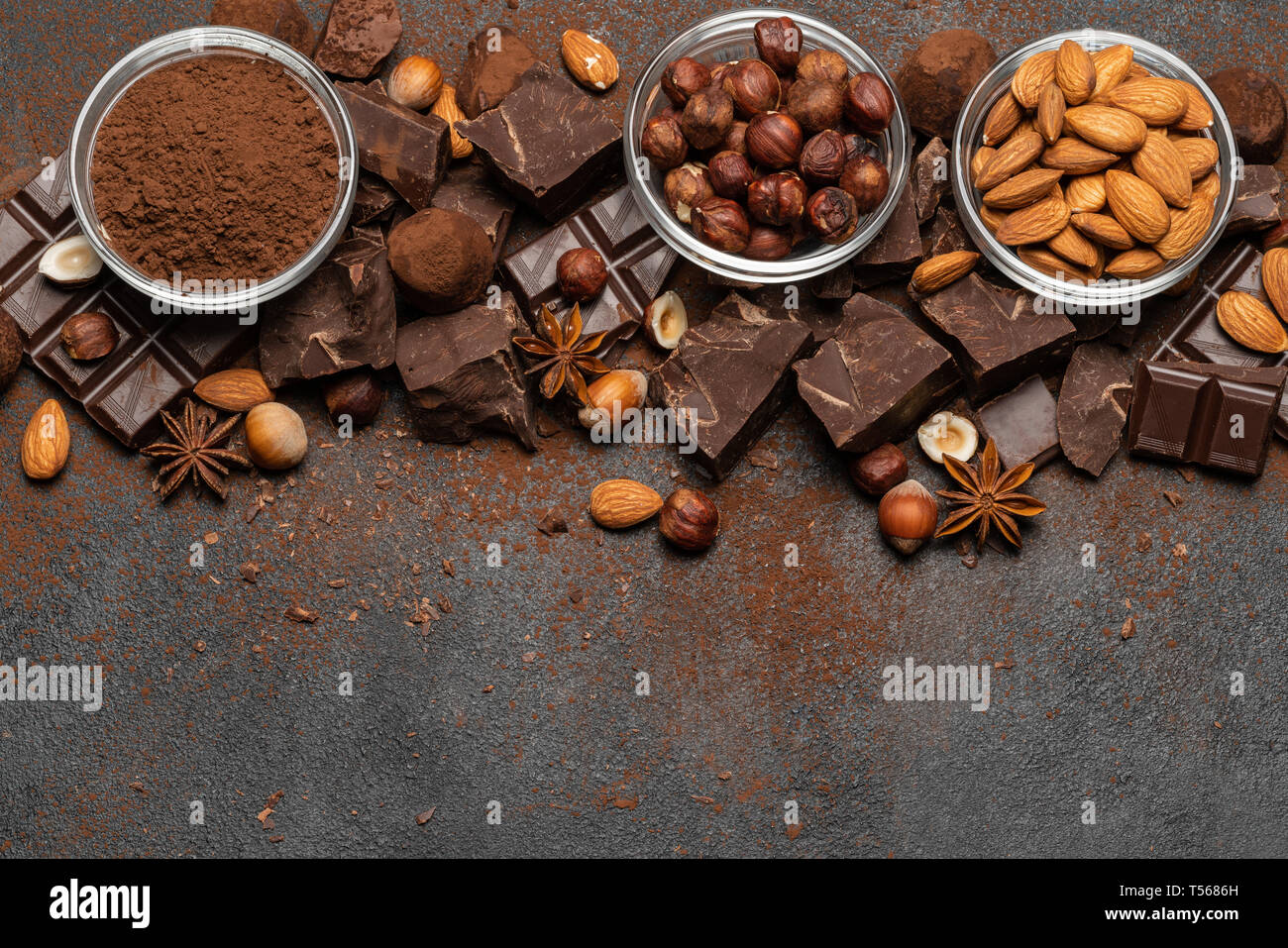Des tas de morceaux de chocolat et les noix brisées sur fond de béton foncé Banque D'Images
