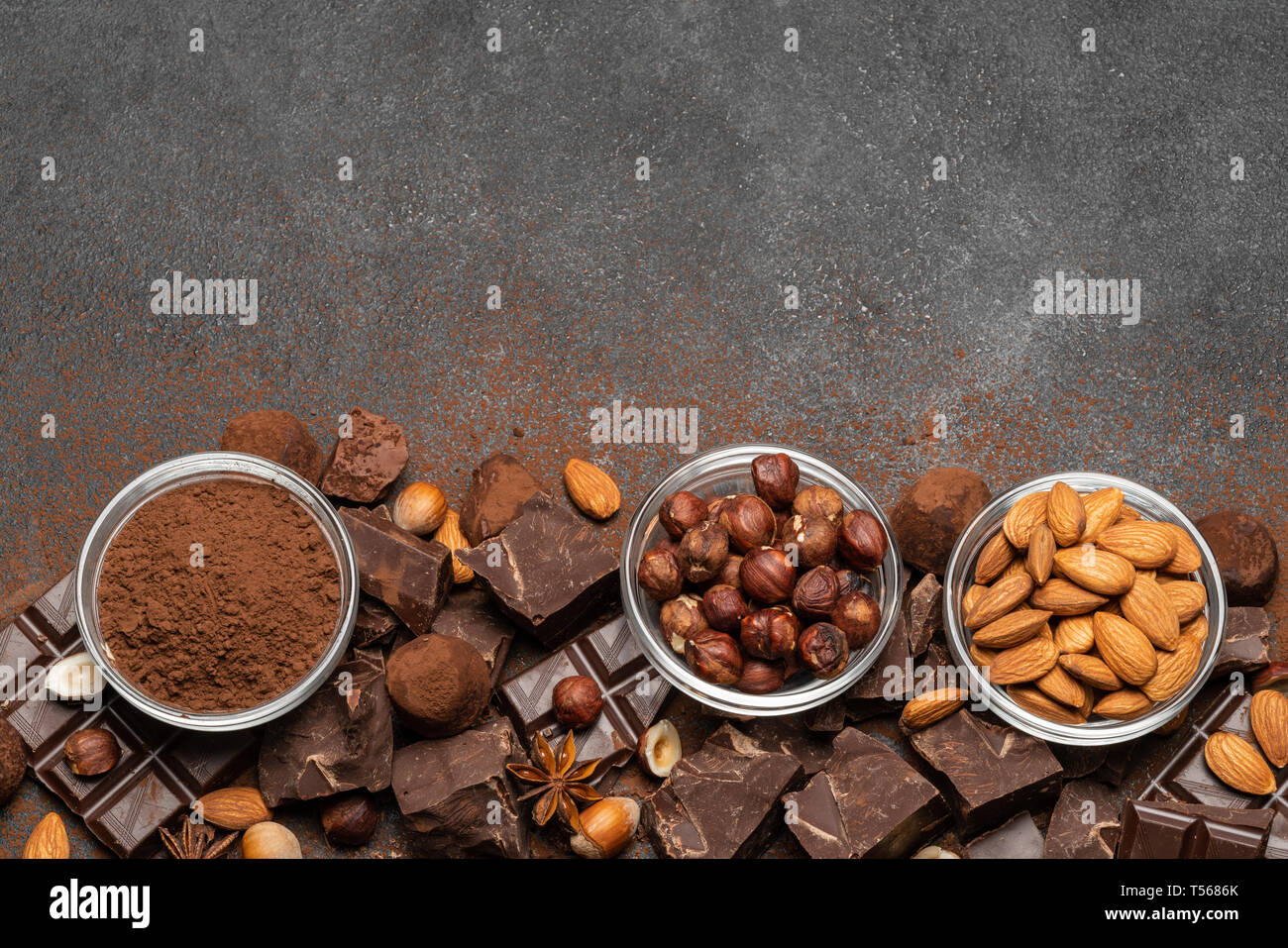 Des tas de morceaux de chocolat et les noix brisées sur fond de béton foncé Banque D'Images