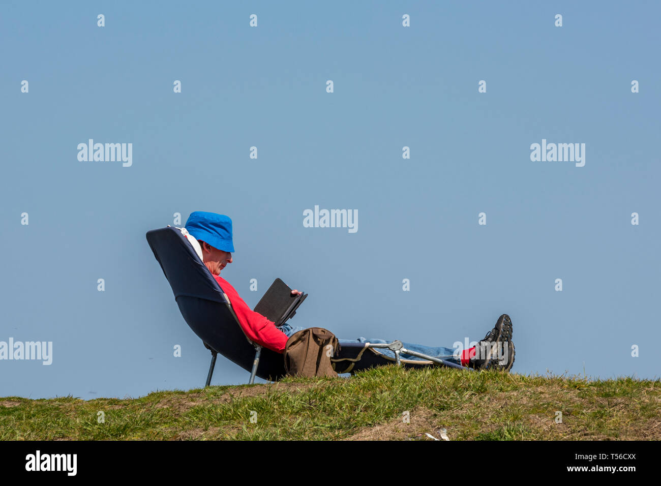 Un homme de vous détendre sur un transat à l'été la lecture d'un livre  Photo Stock - Alamy