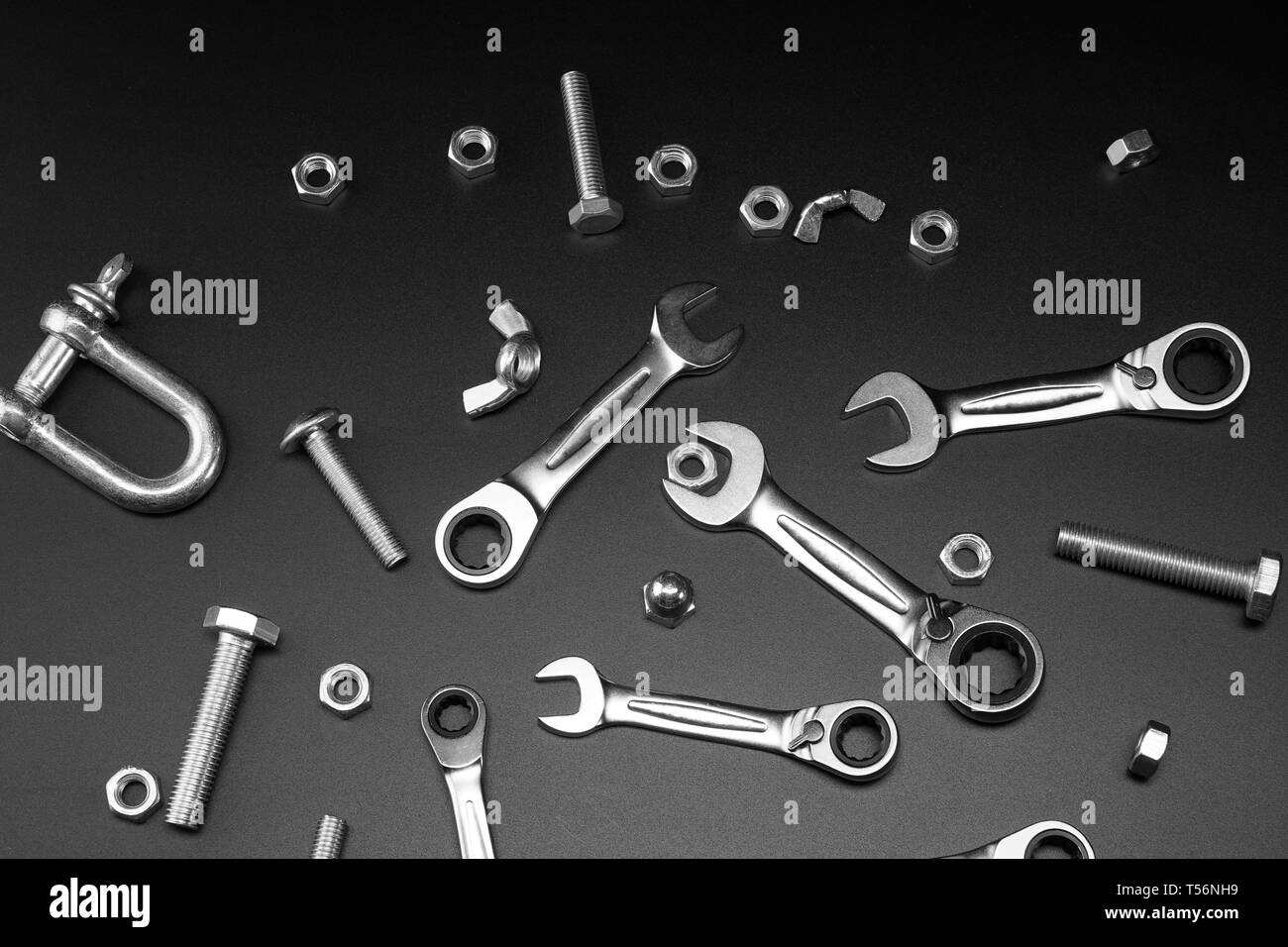 Écrous, boulons, clé à cliquet, sur un fond sombre. Pour la fixation des outils de liaisons vissées. Banque D'Images