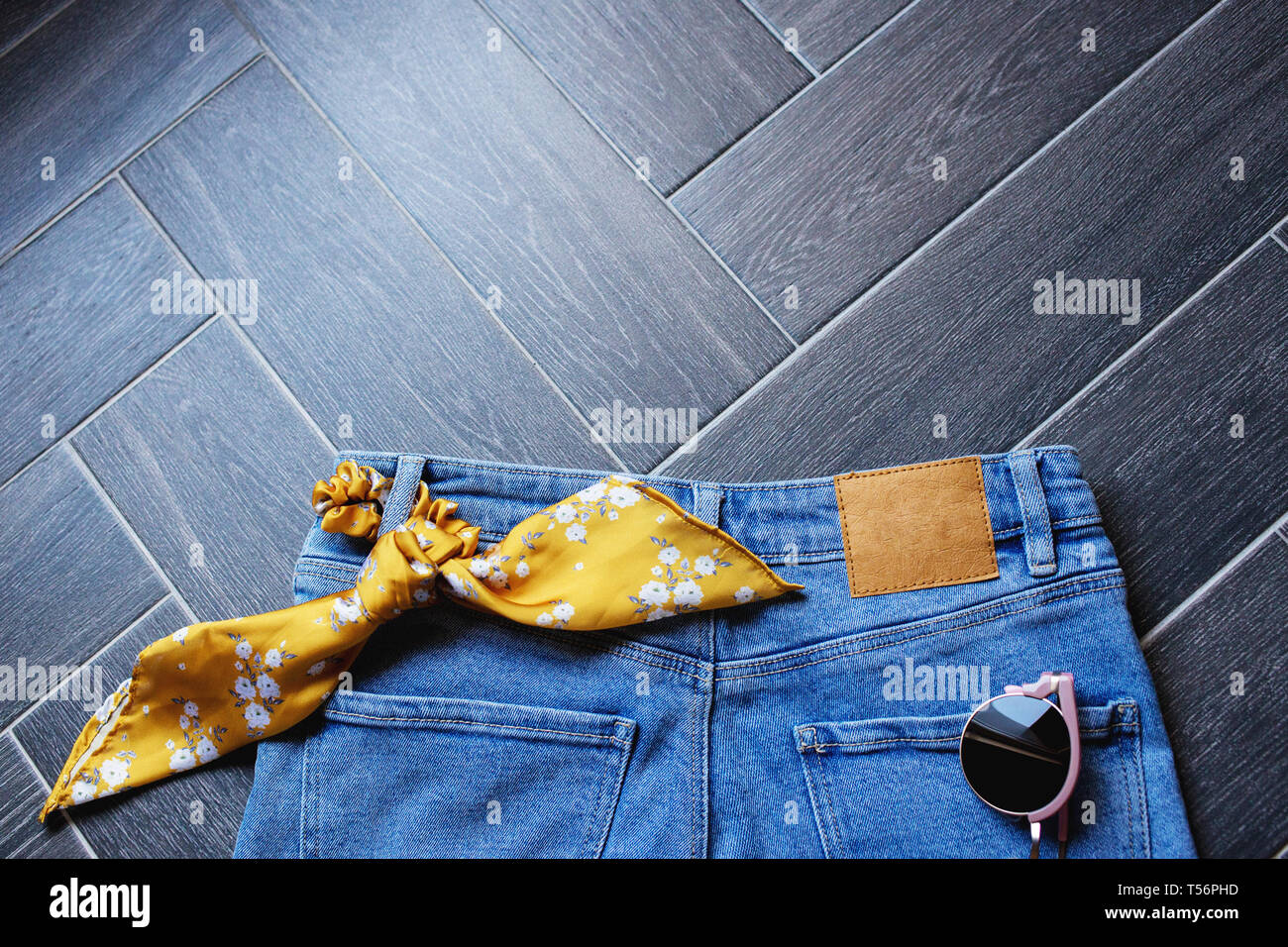Vêtements de denim bleu, lunettes de soleil, des animaux et de la courroie d'impression ruban jaune moutarde à la mode pour les cheveux sur l'arrière-plan en bois gris clair. Immersive pour la mode bl Banque D'Images