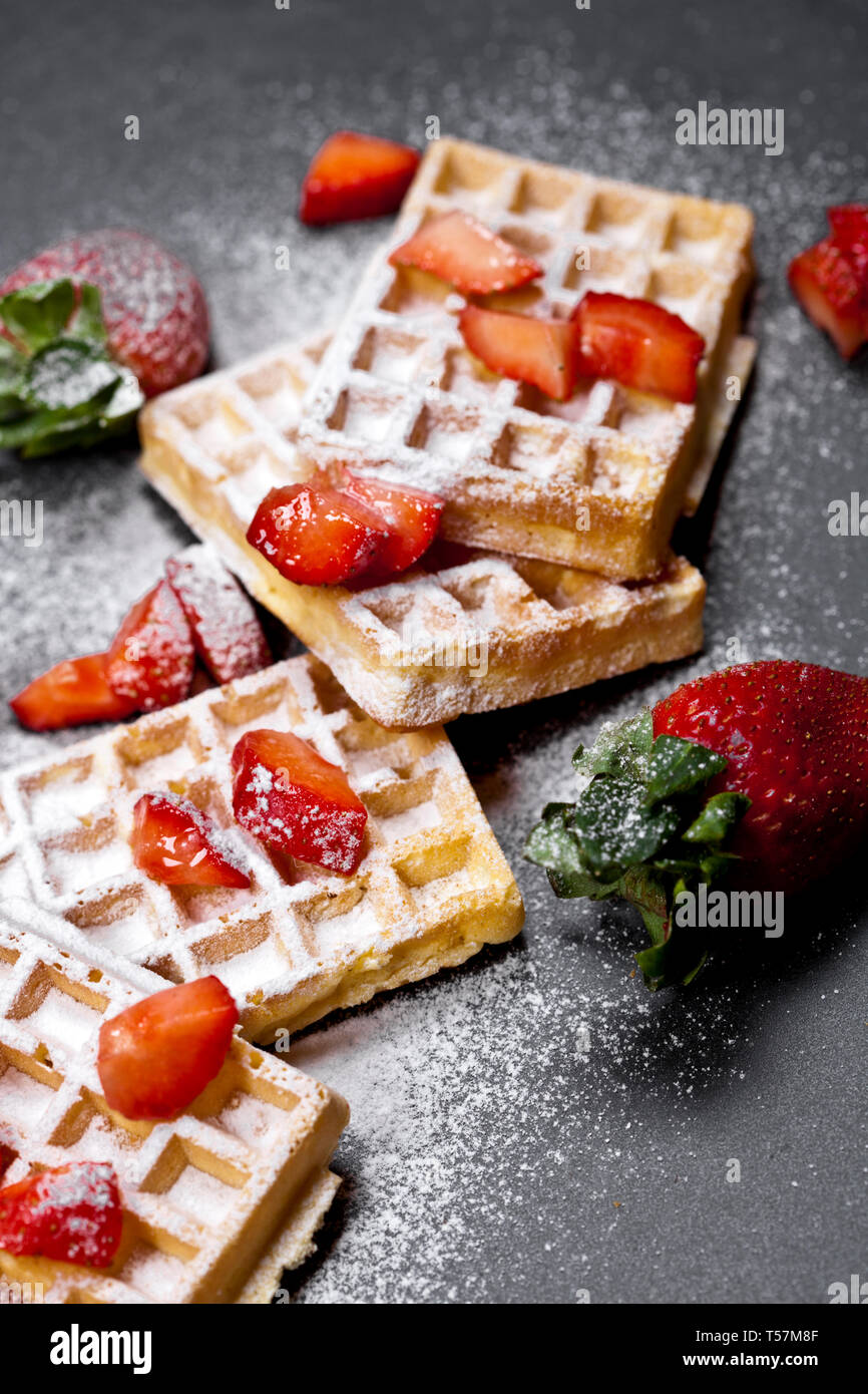 Belgique waffers avec des fraises et du sucre en poudre sur tableau noir l'arrière-plan. Banque D'Images