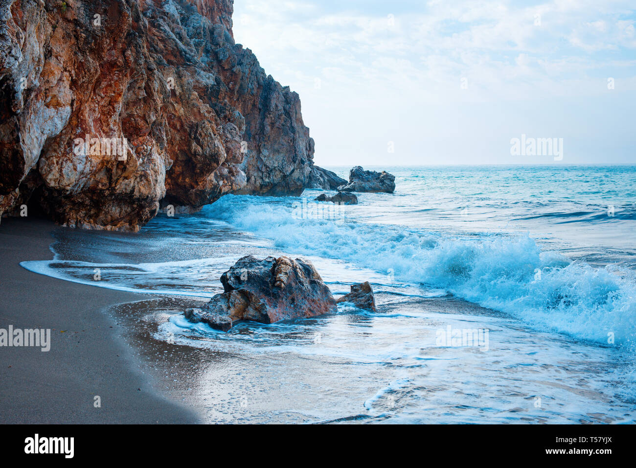 Belle plage de sable et des vagues de l'océan bleu avec mousse blanche près de grotte. Banque D'Images