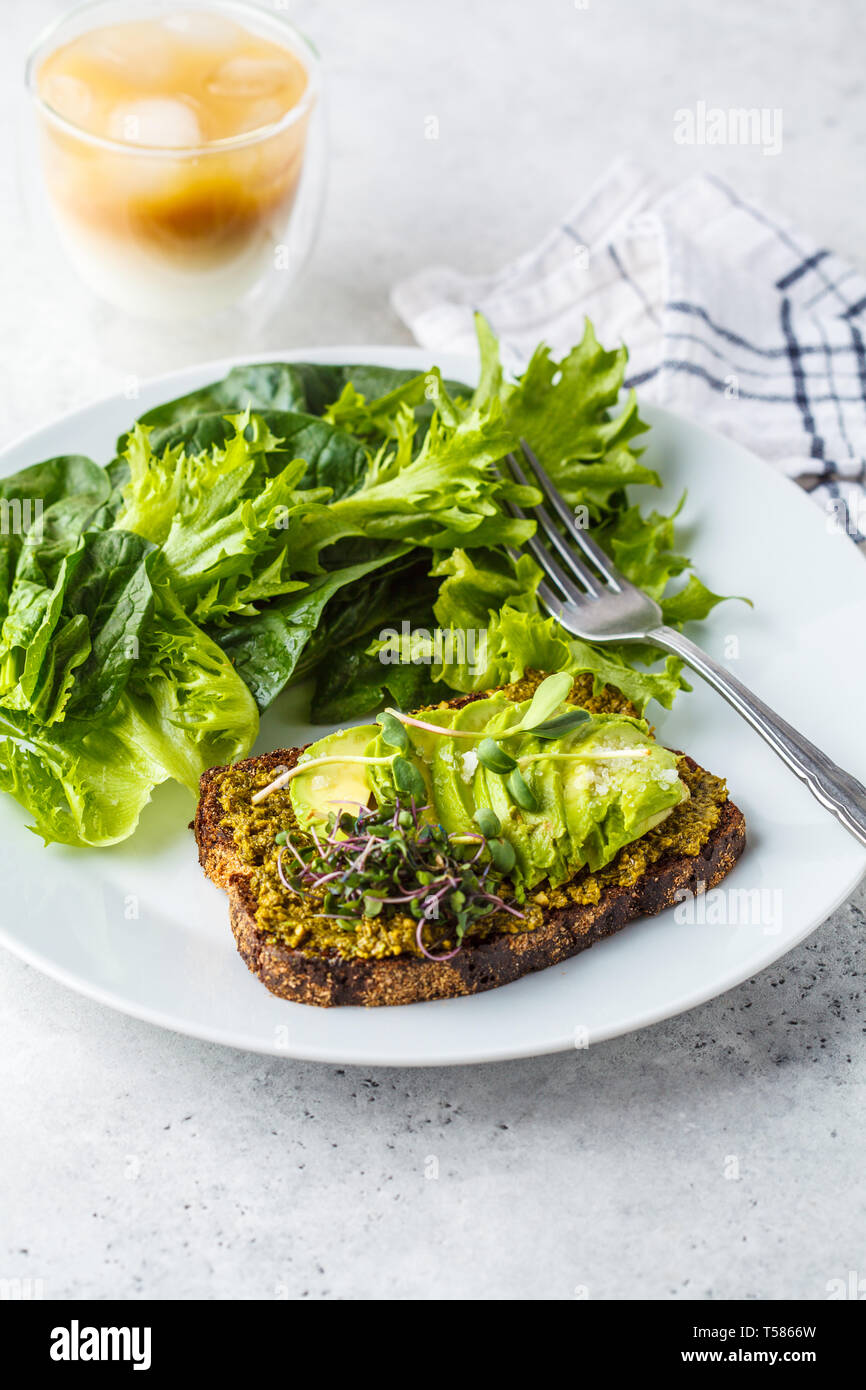 Toast à l'avocat avec du pesto, salade de choux et sur une assiette blanche et de glace café. Banque D'Images